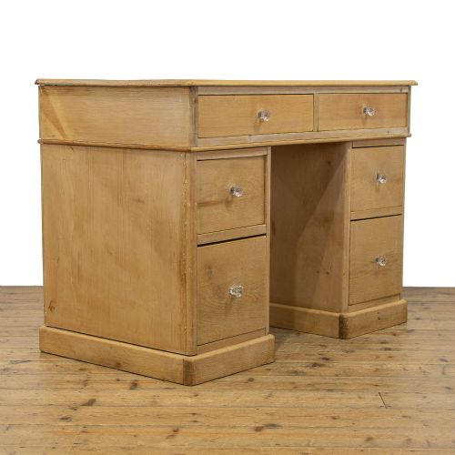 fig 1. An antique natural pine kneehole desk featuring twin pedestals, six lower drawers, two upper frieze drawers, and clear glass knobs.