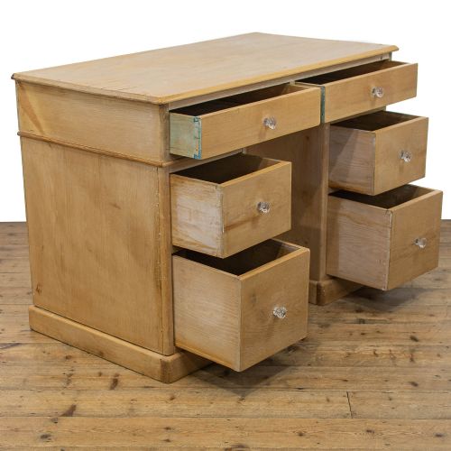 fig 2. An antique natural pine kneehole desk featuring twin pedestals, six lower drawers, two upper frieze drawers, and clear glass knobs.