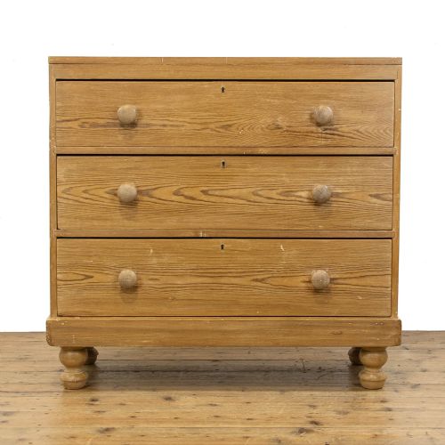 fig 1. A Victorian waxed pine chest of drawers with three full-width drawers, turned wooden handles, and bun feet.