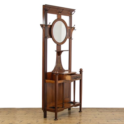 fig 3. An Edwardian mahogany hall stand featuring a central circular mirror, marquetry inlay, brass coat hooks, a single drawer, and umbrella holders with drip trays.