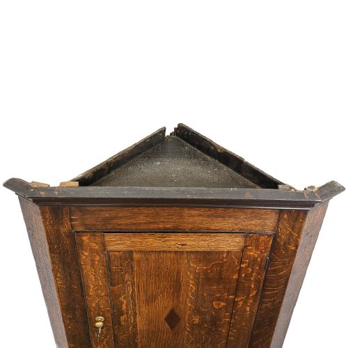 fig 2. An antique Georgian dark oak wall-hanging corner cupboard featuring a moulded top cornice, a single fielded panel door with a central inlaid diamond motif, and a brass keyhole.