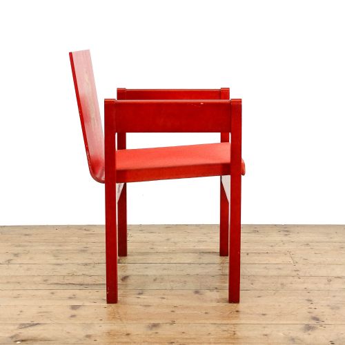 fig 2. A mid-century modern vermilion red wooden armchair featuring a flat square backrest printed with a gold Prince of Wales crest.