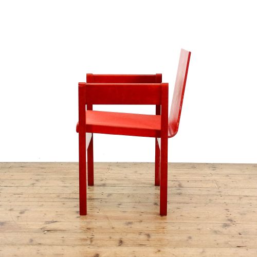 fig 3. A mid-century modern vermilion red wooden armchair featuring a flat square backrest printed with a gold Prince of Wales crest.