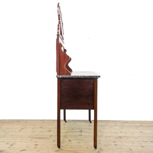 fig 1. An Edwardian mahogany washstand with a grey marble top, a green ceramic tiled splashback, and an arch-framed mirror above a two-door cabinet on castors.