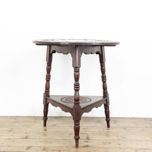 fig 1. An early twentieth-century dark oak cricket table featuring a circular carved top, three turned legs, and a triangular lower shelf.
