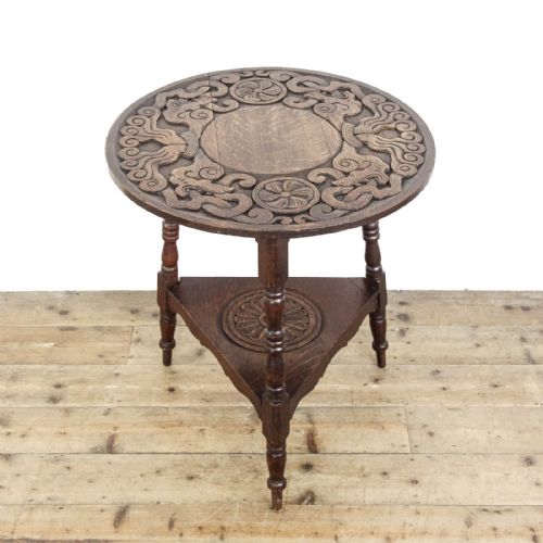 fig 2. An early twentieth-century dark oak cricket table featuring a circular carved top, three turned legs, and a triangular lower shelf.