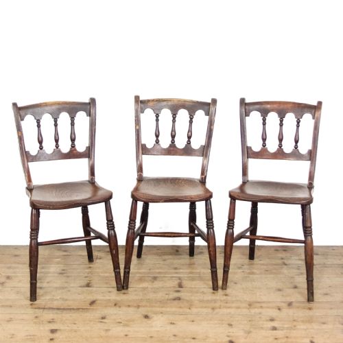 fig 1. A set of three Victorian elm farmhouse dining chairs featuring shaped seats, turned spindles, and dark timber finishes.