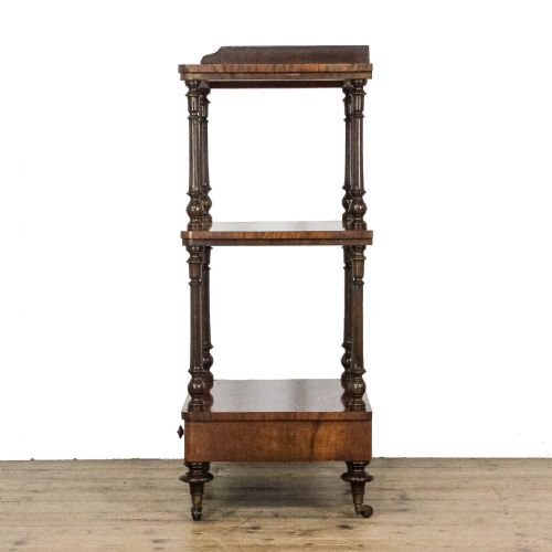 fig 2. A three-tiered Victorian walnut whatnot stand featuring turned support columns, a single base drawer with turned wooden knobs, and brass castors.