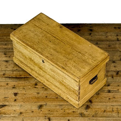 fig 2. A rectangular natural pine blanket box featuring hand-cut dovetail joints, a hinged top lid, a moulded plinth base, and a central metal escutcheon.