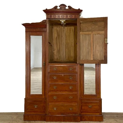 fig 1. A large Victorian mahogany compactum wardrobe featuring a raised central section with carved panels and drawers flanked by two tall mirrored doors.