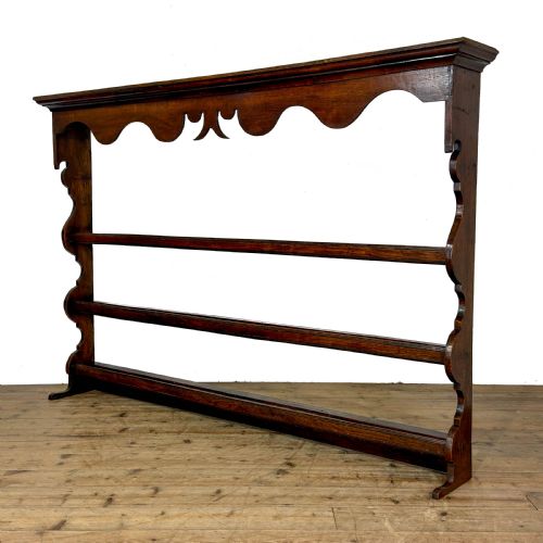 fig 1. A dark oak wooden dresser rack featuring three horizontal shelves and a scalloped top frieze.