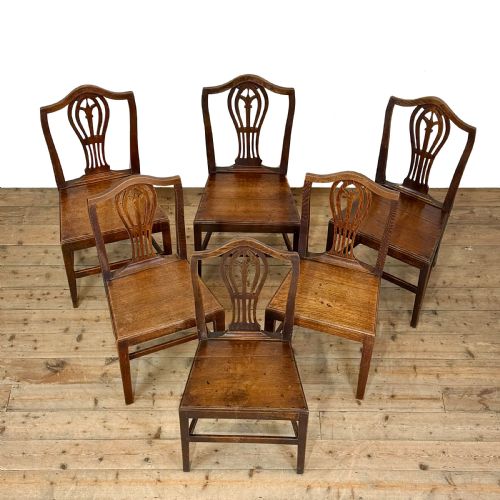 fig 2. A set of six 19th-century oak dining chairs featuring pierced back splats, solid wooden seats, and straight legs connected by stretchers.
