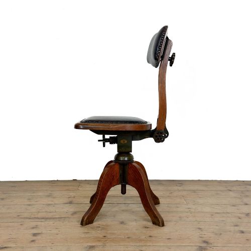 fig 1. An early 20th-century oak swivel desk chair featuring dark studded leather upholstery, a curved lumbar backrest, and a four-star wooden base.