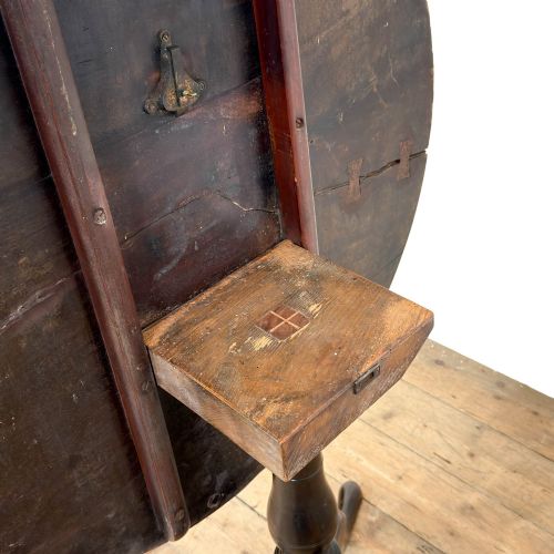 fig 1. An antique George III mahogany tripod table featuring a circular tilt top shown in the upright position above a turned column and three down-swept legs.