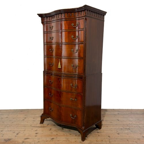 fig 1. A tall mahogany serpentine chest on chest featuring two stacked sections of graduating drawers with brass handles and carved cornice detail.
