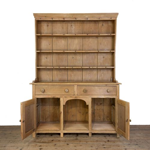 fig 1. A tall Victorian pine kitchen dresser with open plate shelving, cup hooks, two drawers, panelled doors, and a central open alcove.