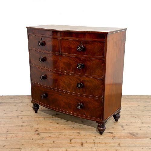 fig 1. A Victorian mahogany bow front chest of drawers with two short over three long drawers, turned wooden knobs, and turned feet.