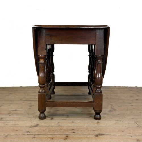 fig 2. An 18th-century dark oak gateleg table featuring two hinged drop leaves, turned legs, and lower stretchers.