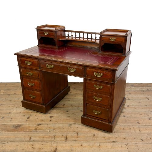 fig 1. An antique Victorian mahogany pedestal desk featuring a raised gallery superstructure, multiple drawers, and brass handles.