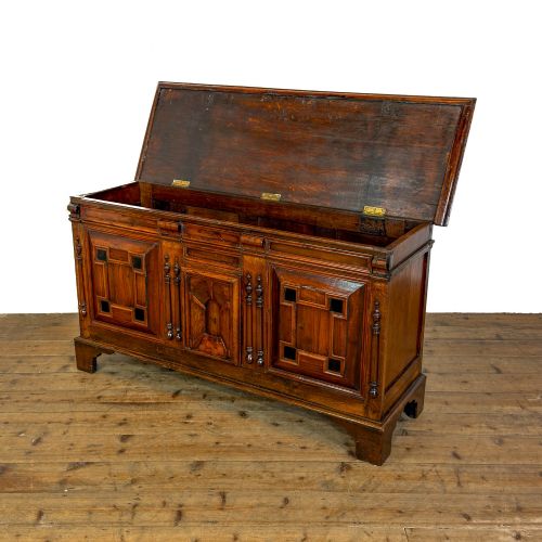 fig 1. A seventeenth-century style carved oak coffer featuring geometric panelling, split baluster turnings, and dark square inlay details on a plinth base.