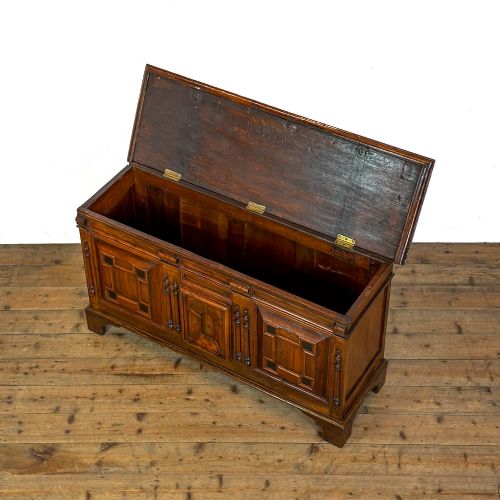 fig 2. A seventeenth-century style carved oak coffer featuring geometric panelling, split baluster turnings, and dark square inlay details on a plinth base.
