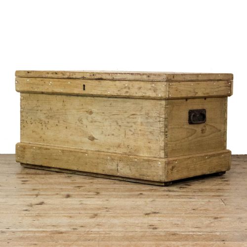 fig 1. A rectangular natural pine storage chest featuring visible hand-cut dovetail joinery, a fitted flat lid, a central keyhole escutcheon, and a thick timber plinth base.