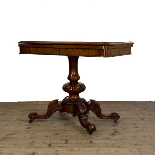 fig 1. An antique Victorian walnut foldover card table featuring a rectangular swivel top, turned central column, and carved scroll feet.