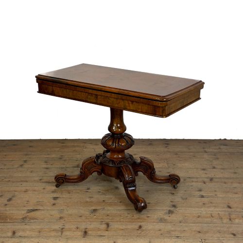 fig 2. An antique Victorian walnut foldover card table featuring a rectangular swivel top, turned central column, and carved scroll feet.
