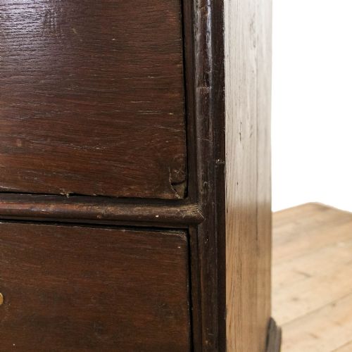 fig 1. An eighteenth-century dark oak chest of drawers featuring a two-over-three drawer configuration, brass swan-neck handles, decorative keyhole escutcheons, and shaped bracket feet.
