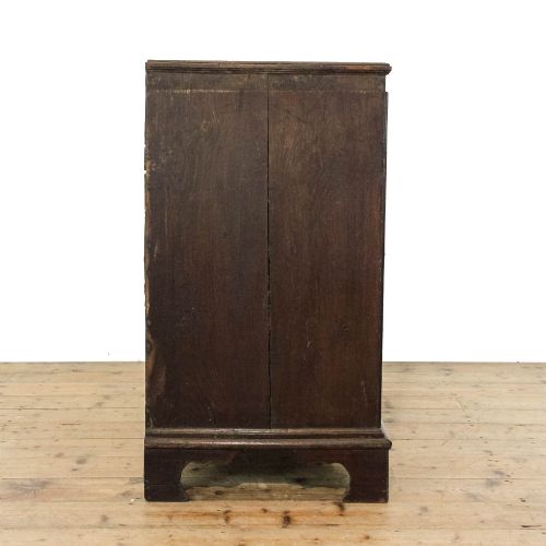 fig 2. An eighteenth-century dark oak chest of drawers featuring a two-over-three drawer configuration, brass swan-neck handles, decorative keyhole escutcheons, and shaped bracket feet.