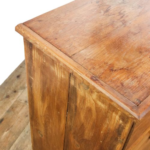 fig 1. An antique pine chest of drawers featuring three wide drawers with turned wooden knob handles and a low plinth base.