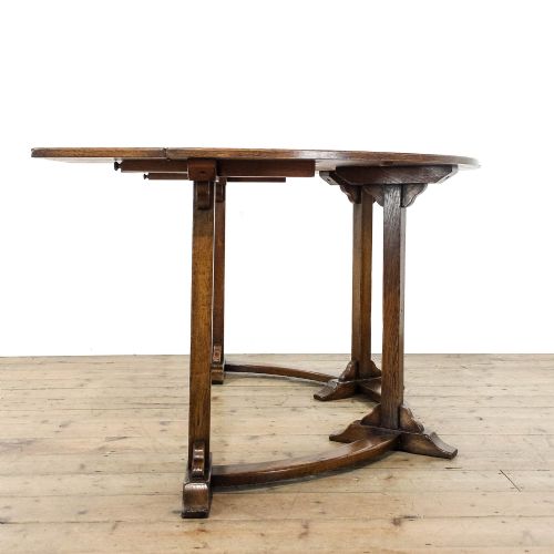 fig 2. An antique dark oak horseshoe-shaped hunt table featuring upright trestle supports and a curved base stretcher.