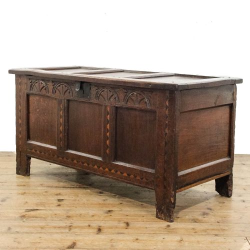fig 2. A dark carved oak coffer featuring three front panels, geometric inlay along the frame, arcaded frieze carvings, and a central iron keyhole plate.
