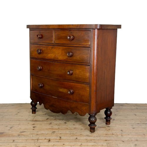 fig 1. A Victorian mahogany chest of drawers featuring a bowfront profile, two short over three long graduating drawers, turned wooden knobs, and turned feet.
