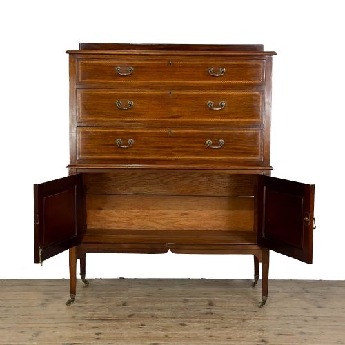 fig 1. An antique Edwardian mahogany tallboy chest featuring three upper drawers above a double-door cupboard with satinwood string inlay and brass castors.