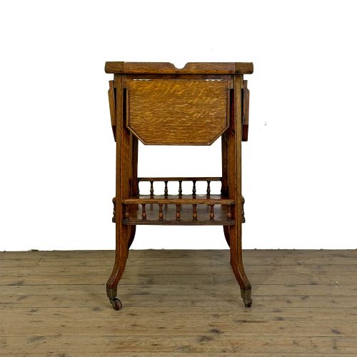 fig 1. An Edwardian medium oak two-tier tea trolley featuring drop-leaf side panels, a spindle-turned gallery on the lower shelf, and brass castors.