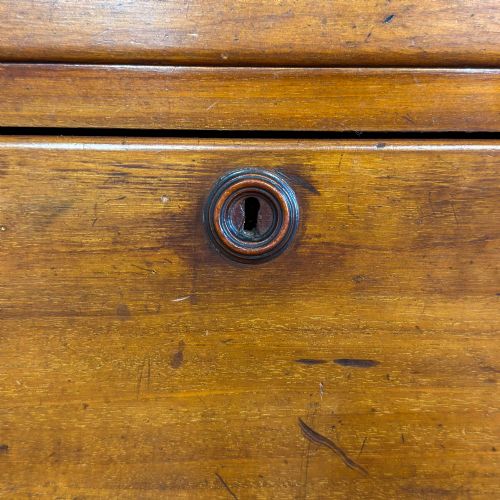 fig 1. A three-drawer Victorian mahogany chest featuring turned wooden knobs and brass keyhole escutcheons set on a plinth base.