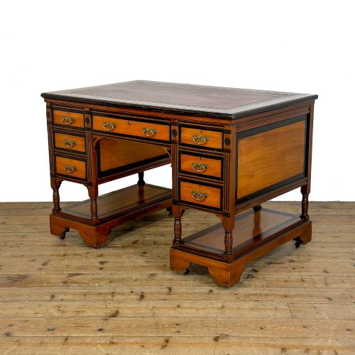 fig 1. An Aesthetic Movement double-sided partners desk crafted from warm brown wood with black ebonised mouldings, brass drop handles, central kneehole drawer, twin pedestals, open lower shelves, and turned columns.