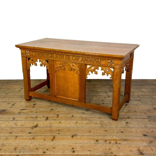 fig 1. A carved oak Gothic Revival chapel altar table featuring trefoil tracery, an inscribed apron in Welsh script, and a solid rectangular top.