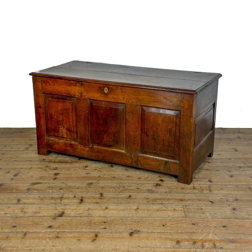 fig 1. A 19th-century warm brown oak coffer featuring three fielded front panels, a brass keyhole escutcheon, and a flat hinged top lid.
