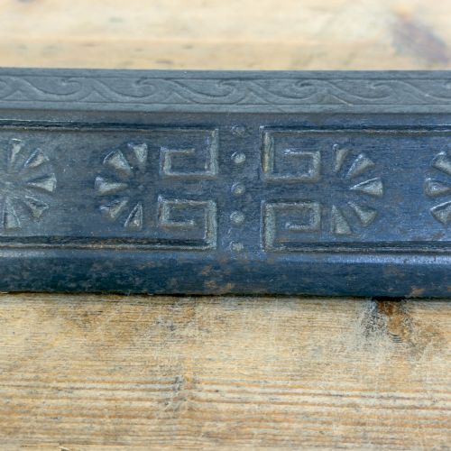 fig 1. An antique Victorian fireplace fender featuring a dark metal base with stamped geometric patterns and an elevated brass rail supported by ribbed finials.