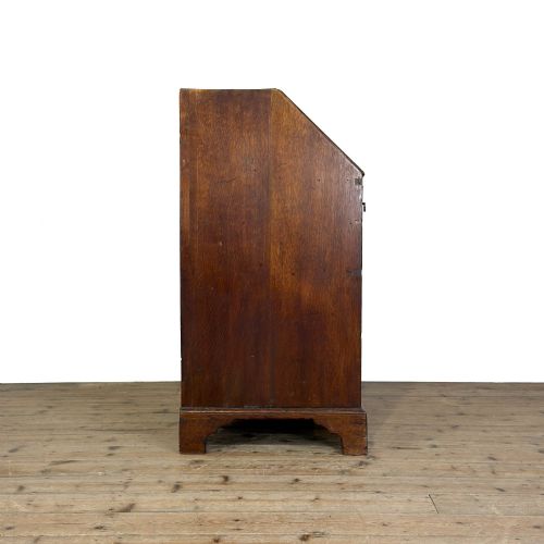 fig 1. An 18th-century oak writing bureau featuring a sloping fall front above four graduated drawers with brass handles and bracket feet.