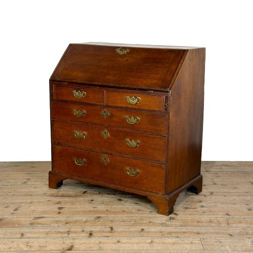 fig 2. An 18th-century oak writing bureau featuring a sloping fall front above four graduated drawers with brass handles and bracket feet.