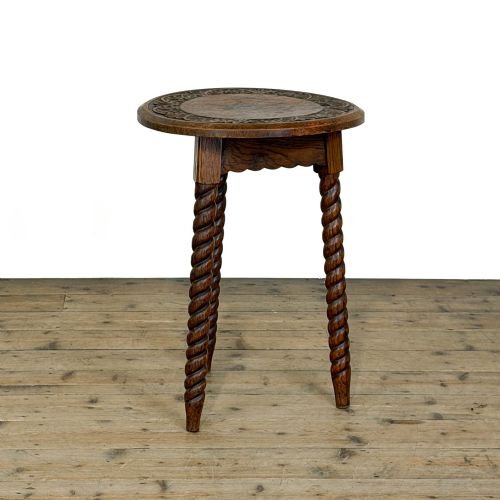 fig 1. A small circular dark oak cricket table featuring a relief-carved top border and three spiral barley twist tripod legs.
