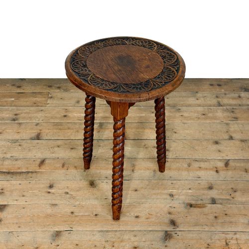 fig 2. A small circular dark oak cricket table featuring a relief-carved top border and three spiral barley twist tripod legs.