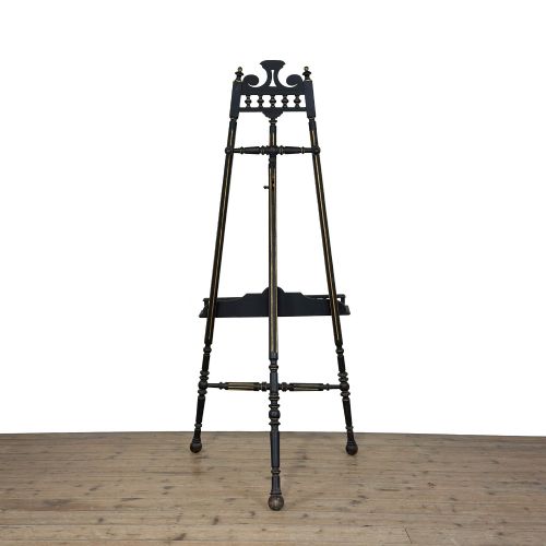 fig 1. An ebonised wooden floor-standing easel with turned legs, geometric carved details, and gold leaf highlights set against a plain background.