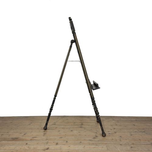 fig 2. An ebonised wooden floor-standing easel with turned legs, geometric carved details, and gold leaf highlights set against a plain background.