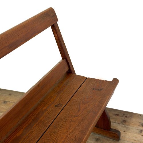 fig 1. An antique pine bench featuring a pivoting backrest mechanism set above a long plank seat and shaped trestle end supports.