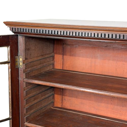 fig 1. A 19th-century dark mahogany low bookcase featuring two glazed doors with geometric astragal glazing bars, dentil moulding at the top cornice, and bracket feet.