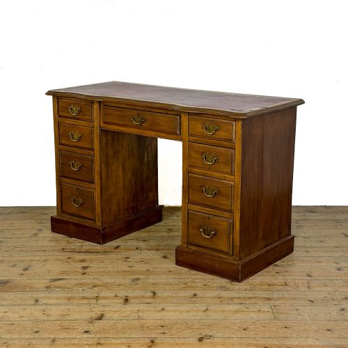fig 1. An Edwardian timber kneehole desk featuring a central drawer flanked by twin pedestals with brass handles and a rectangular top.